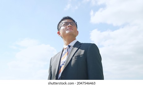 Young Asian Businessman Looking Up At The Sky.