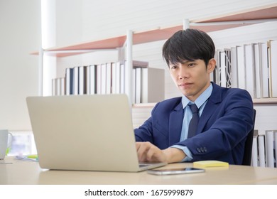 A Young Asian Businessman Sat Seriously On The Desk In The Office.