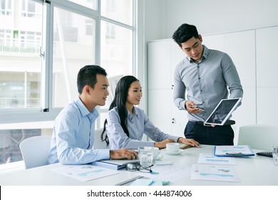 Young Asian Businessman Showing Presentation On Tablet Computer To Investors