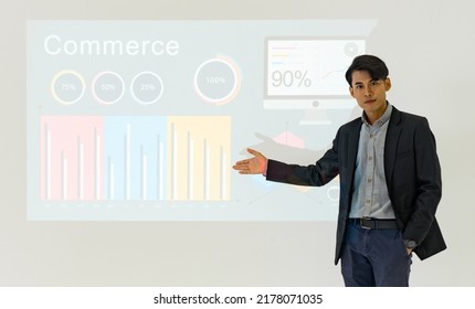 Young Asian Businessman In Suit Giving Presentation With Projector Screen. White Wall With Financial Report And Lecturer. Training Staff, Meeting, Report, Business School.