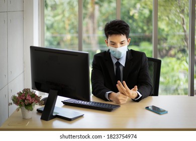 A Young Asian Businessman In Suit Wearing Face Mask For Protective Covid-19 Sits At His Desk In The Office Give Himself A Hand Massage After Working On A Computer All Day.