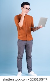 Young Asian Businessman Using Laptop On Blue Background