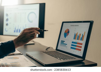 Young Asian businessman working with laptop, checking graphs, company budget reports, production control. Operational inspection cost plus price Close-up pictures