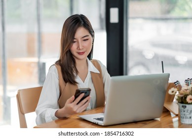 Young asian businesswoman beautiful charming smiling and using on mobile phone in the office. - Shutterstock ID 1854716302