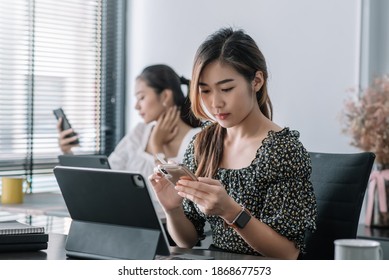 Young asian businesswoman beautiful charming smiling and using tablet and mobile phone, while sitting at table and working in office. - Shutterstock ID 1868677573