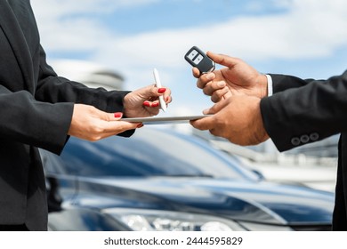 Young asian businesswoman buying new car with sale manager signing signature deal on tablet getting key and go to driving car. Buy sell rent concept. Hand sending key vehicle contract car deal - Powered by Shutterstock