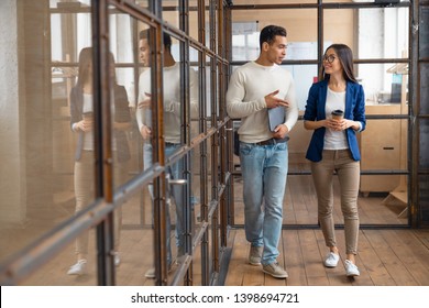 Young Asian Businesswoman Discussing With Her Colleague In The Office Building. Two Business People Walking And Talking Over Work Questions