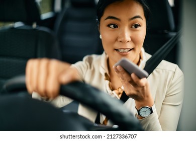 Young Asian Businesswoman Driving Car And Talking Over Cell Phone's Speaker. 