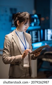 Young Asian Businesswoman In Formalwear Scrolling In Tablet While Searching In The Net For New Methods Of Decoding Digital Data