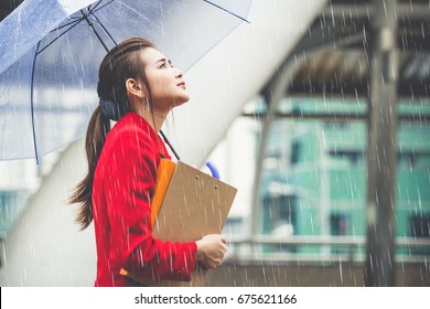 Young Asian Businesswoman Holding Business Documents And Umbrella Walking Under Raining In The City