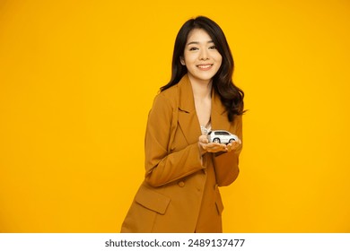 Young Asian businesswoman holding car model isolated on yellow studio background, Car Insurance concept - Powered by Shutterstock