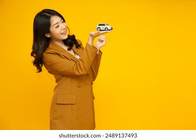 Young Asian businesswoman holding car model isolated on yellow studio background, Car Insurance concept - Powered by Shutterstock