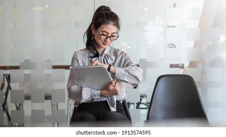 Young Asian businesswoman holding a portfolio looks at the clock waits for a job interview at the office.