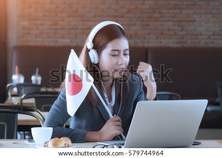 Young asian businesswoman listening online match by computer laptop, playing game and  cheer Japan team.