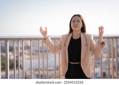 Young asian businesswoman practicing mindfulness with a breathing exercise on a rooftop at sunset, promoting mental wellness and stress relief in a corporate setting - Powered by Shutterstock