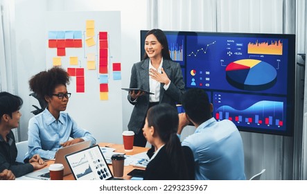 Young asian businesswoman presenting data analysis dashboard on TV screen in modern meeting. Business presentation with group of business people in conference room. Concord