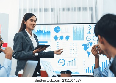 Young asian businesswoman presenting data analysis dashboard on TV screen in modern meeting. Business presentation with group of business people in conference room. Concord - Shutterstock ID 2311034029