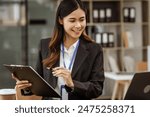 A young Asian businesswoman is seen diligently working at her desk. She