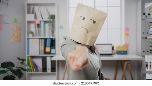 Young Asian businesswoman sit desk wear draw sad mask paper craft bag feel bad mood and fail work project at office  Anonymous young lady mad   blame and overwork  Work mental health 