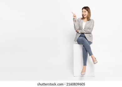 Young Asian businesswoman sitting and pointing to empty copy space isolated on white background - Powered by Shutterstock