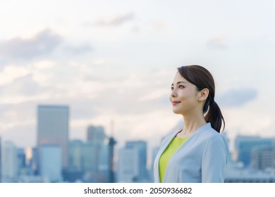 Young asian businesswoman smiling in front of the city.