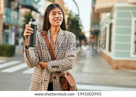 Young asian businesswoman smiling happy holding bottle of water at the city.