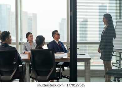 Young Asian Businesswoman Speaking To Team Of Businesspeople In Meeting In Conference Room