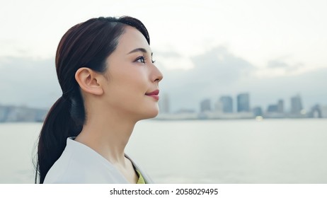 Young Asian Businesswoman Staring Into The Distance In Front Of The City.