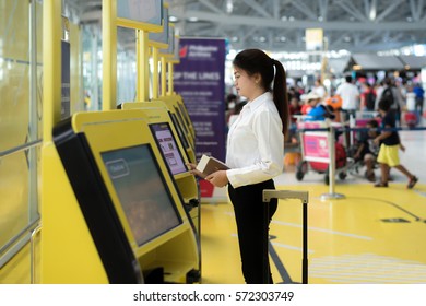 Young Asian businesswoman using self check-in kiosks in airport. Technology in airport.