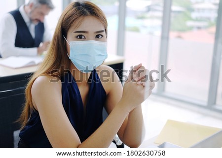 Young Asian businesswoman wearing mask preventing for Covid 19 virus and working in internationnal office. Social distance and new normal lifestyle concept