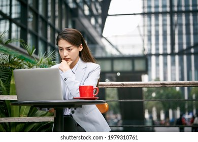 young asian businesswoman working outdoors in coffee shop using laptop computer