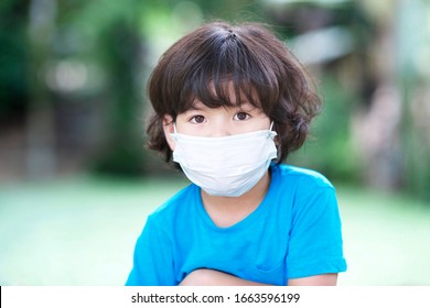 Young Asian Child With Facemask In Outdoor.Chinese Boy With Face Mask.Cute Kid With Protection From Influenza And Coronavirus Illnesses.Wuhan Outbreak Prevention Kit.Preschooler Safe From Virus.