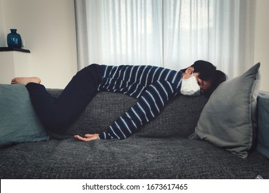 Young Asian child lying exhausted on sofa wearing a mouth mask (concept home quarantine)