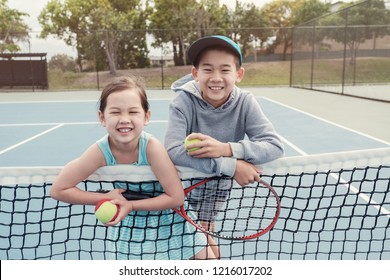 Young Asian children tennis beginner player on outdoor blue court