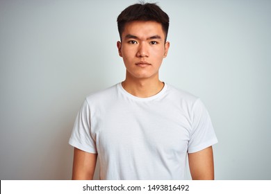 Young Asian Chinese Man Wearing T-shirt Standing Over Isolated White Background Relaxed With Serious Expression On Face. Simple And Natural Looking At The Camera.