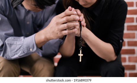 Ein junges christliches Paar aus Asien betet in einer Kirche zu Jesus Christus.