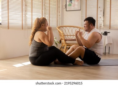 Young Asian Chubby Couple Exercising And Working Out Together In Living Room At Home. Plus Size Man And Woman Cheering Up And Show Positive Energy And Encourage Each Other That They Can Do It