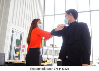 Young Asian Colleagues Wearing Face Masks Meeting At The Office And Greeting Each Other By Elbow Bumping For Social Distancing And Good Hygiene At Workplace During Covid 19 Virus Outbreak Concept