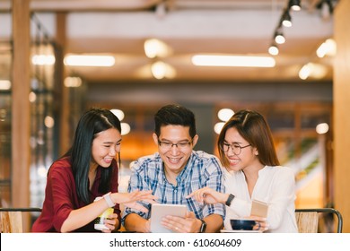 Young Asian college students or coworkers using digital tablet together at coffee shop, diverse group. Casual business, freelance work at cafe, social meeting, or education concept - Powered by Shutterstock