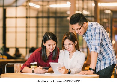 Young Asian college students or coworkers using digital tablet and smartphone together at coffee shop, diverse group. Casual business, freelance work at cafe, social meeting, or education concept - Powered by Shutterstock