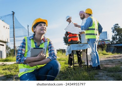 Young Asian construction engineer woman holding tablet working in construction site with Arab developer and contractor discussing background