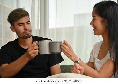 Young Asian couple clink a mug together, Domestic life and Domestic home concept.