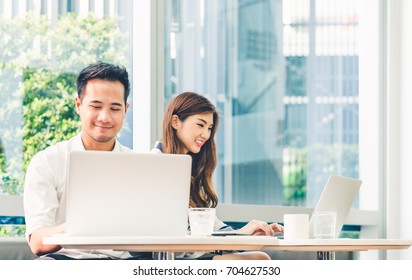 Young Asian Couple Or College Student Using Laptop Computer Notebook Work Together At Coffee Shop Or University Campus. Information Technology, Cafe Lifestyle, Office Meeting, Or E-learning Concept