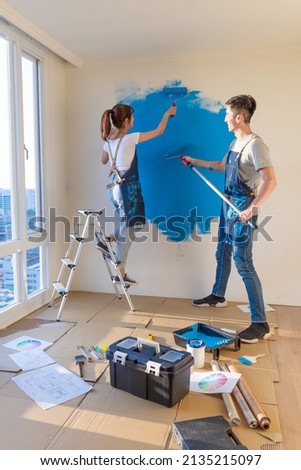 young asian couple decorate home - they painting wall with blue color together