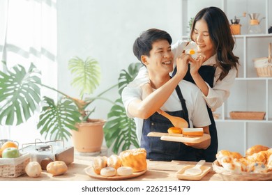 Young Asian couple doing holiday together in the kitchen happily wearing apron. love and valentine concept - Powered by Shutterstock