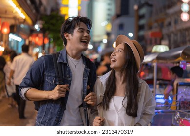 Young Asian couple enjoy and have fun outdoor lifestyle together in street market on summer holiday vacation in bangkok, thailand. Happy man and woman feeling surprise about how beautiful the city is