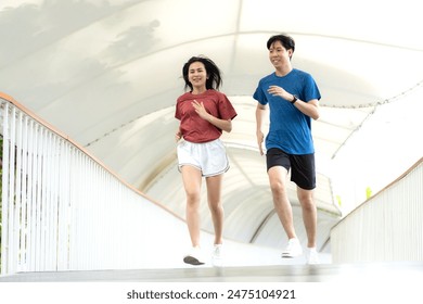 Young Asian couple exercising jogging outdoors in park. Happy runner in sports clothing running outside in urban city in the morning. Wellbeing healthy lifestyle person. Copy space. - Powered by Shutterstock