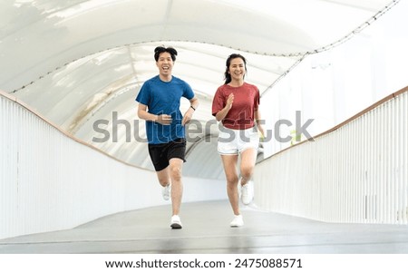 Young Asian couple exercising jogging outdoors in park. Happy runner in sports clothing running outside in urban city in the morning. Wellbeing healthy lifestyle person. Copy space.