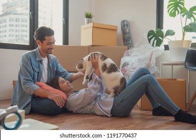 Young Asian Couple Or Family Feeling Happy Relaxing And Play With Their Cat After Moving To New House Or Apartment.