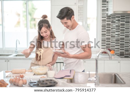 young asian couple happy make bakers helping to make bakery see recipes form tablet 